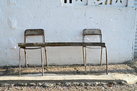 An improvised bench made of a wooden plank and metal chairs against a whitewashed house wall; rustic seating and a rural everyday scene in Kirklareli, Thrace, Turkey