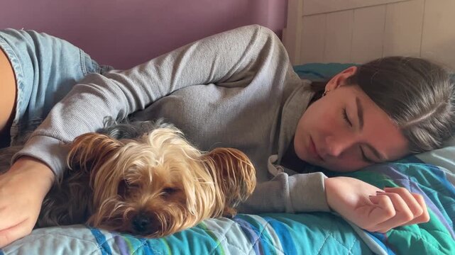 A young blonde woman and her adorable Yorkshire Terrier sleep embraced in a moment of pure affection. The peaceful scene evokes feelings of love, care, friendship, and deep calm.