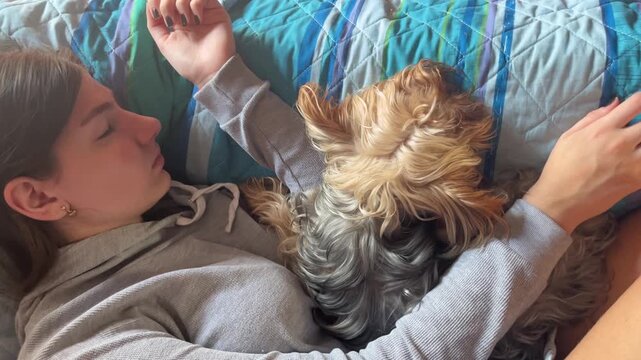Young woman and her adorable yorkshire terrier sleeping peacefully together in bed, sharing a moment of tranquility, pure affection, and deep relaxation