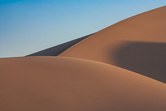Beautiful minimal abstract landscape of sand dunes under a clear blue sky