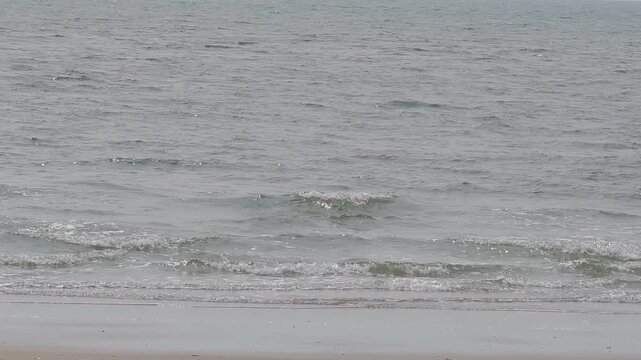 A white beach with ocean waves photographed in natural daytime light.