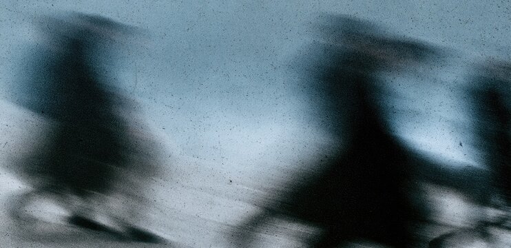 Blurred figures in motion against a pale, textured sky