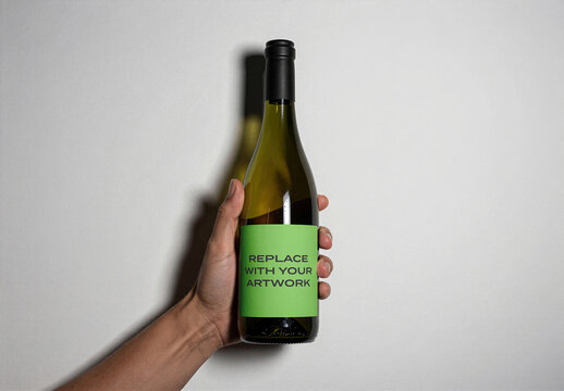 Wine bottle label mockup held in hand against a white wall, with placeholder text, vertical orientation, product packaging presentation, branding display, template for graphic design