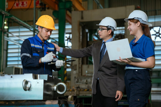 Three professional engineer man and woman manager leader wearing helmet and walking in factory talking and discussing for work