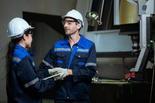 Diverse factory engineers using digital tablet discussing production plan in manufacturing plant industrial. Workers team working together for machinery maintenance service quality control