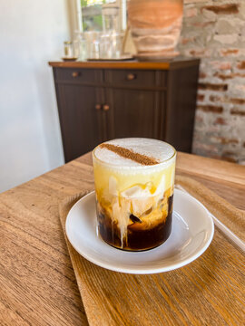 Iced Coffee with Creamy Foam and Cocoa powder on Wooden Tray. Butterscotch cinnamon latte