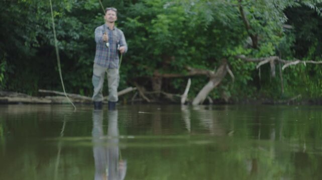 Young adult fisherman fly fishing on the small shallow river and casts