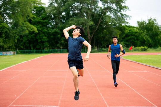 Athletes sprinting on outdoor running track as leading runner celebrates victory, showing race, competition, speed, fitness, endurance, success and energetic sports achievement
