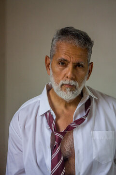 Portrait of Senior Businessman with Loose Tie Looking at Camera