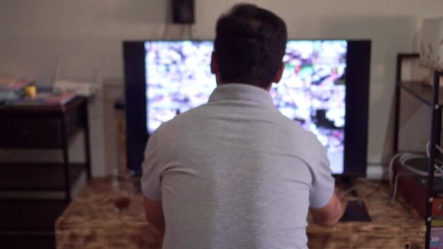 Back view of man watching live security camera feeds on dual screens, dark control room, CCTV monitoring and surveillance system observation concept.