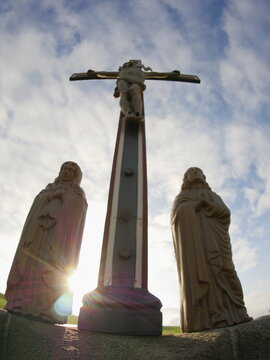 Cross is in the middle of three statues of women