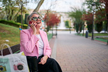 Fototapeta premium Senior woman enjoying phone call in park laughing