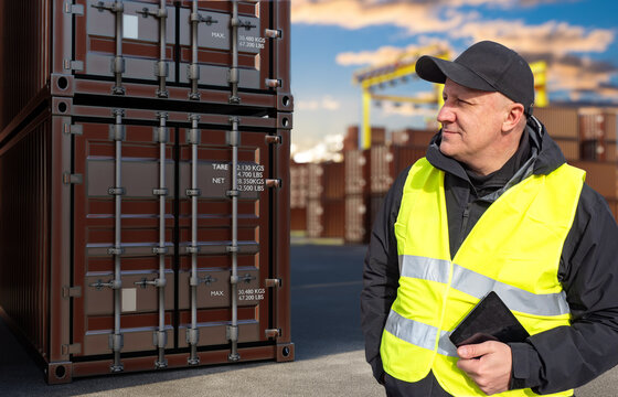 Container logistics. Port worker inspects stacked shipping containers and uses a tablet to manage cargo handling, storage and transportation operations.