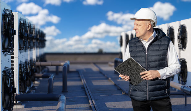 HVAC maintenance. Engineer inspects rooftop air conditioning units and refrigeration equipment to control cooling performance and building climate systems.