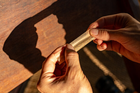 Hands Rolling Cannabis Joint with Silhouette Shadow on Wood