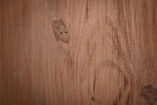 Rustic brown wood surface showing natural timber grain and texture with a circular knot detail, creating an aged background or wall for carpentry, flooring, and interior design concepts.
