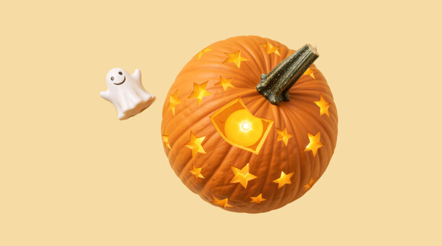 Carved pumpkin with glowing candle and ghost decoration