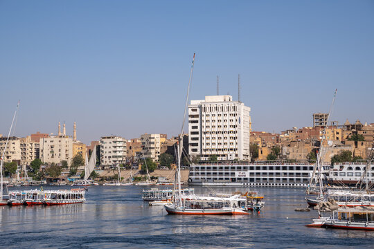 Aswan, egypt - march 10 2026: felucca boats and cruise ships navigating the nile river along aswan's waterfront from Luxor
