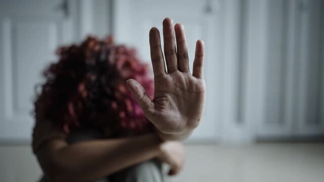 Person stopping or blocking action with raised hand in dimly lit indoor setting