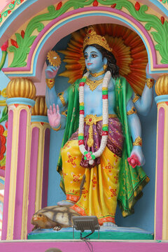 Colorful painted cement wall relief of Hindu god Vishnu stepping on the giant Kurma tortoise avatar.