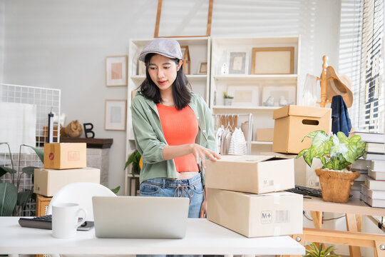Small business owner standing at her desk, carefully arranging cardboard parcel boxes for customer shipping in her shop.