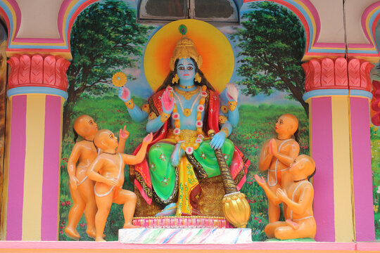 Colorful painted cement wall relief depicting Lord Narayana with the Four Kumaras sages inside a temple niche.