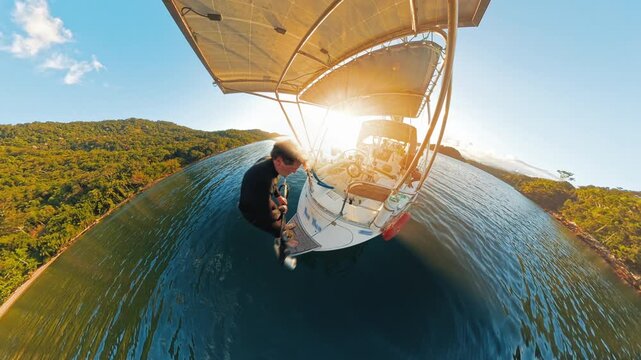 Person prepares for spearfishing from the small sailing boat anchored in the calm lagoon