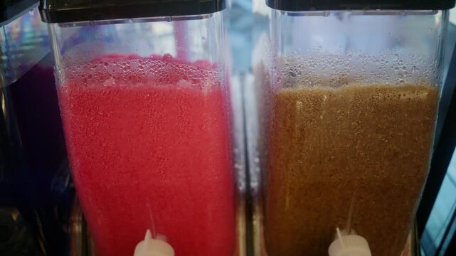 Close up of a slushie dispenser with condensation, serving a vibrant red frozen beverage, ideal for summer refreshment