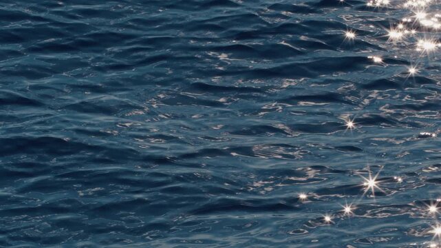 Sea surface with blinking stars and flares as seen from the moving sailing boat