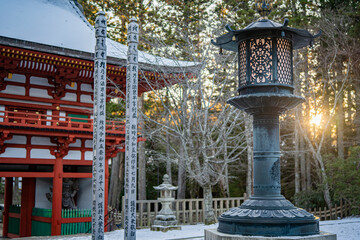 Sunlight illuminating red temple building and stone lantern in forest grounds at Mount Rokko Kobe Japan © Pixels and Shots