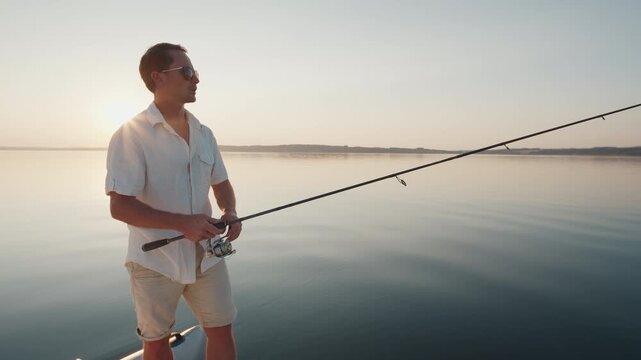 Young man fishing on the river during sunset and casts a lure