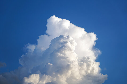 Fluffy White Cumulus Cloud Billowing Against a Vibrant Blue Sky, Peaceful Nature Background