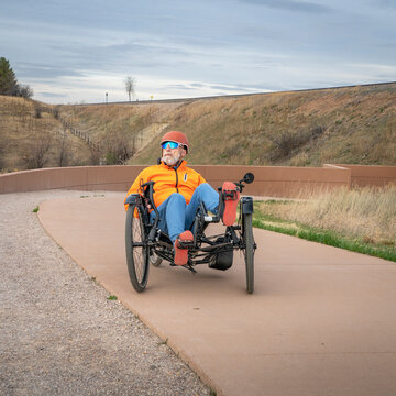 senior cyclist is riding a recumbent tricycle on a paved biking trail in Fort Collins, Colorado
