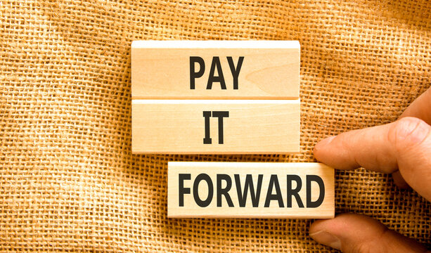 Pay it forward words symbol. Concept words Pay it forward on beautiful wooden blocks. Beautiful canvas background. Businessman hand. Business and pay it forward concept. Copy space.