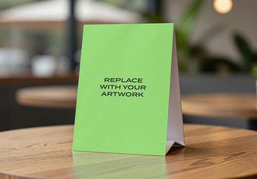 Vertical table tent mockup on a wooden surface in cafe interior with blurred background, realistic presentation for branding, advertising, or informational display