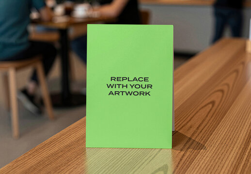 Vertical card mockup on a wooden table in cafe interior with blurred background, realistic stationery presentation for branding, graphic design, advertising, or print media