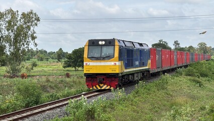 Freight Train Hauling Red Shipping Containers through Rural Landscape in Thailand © Kauncheewa
