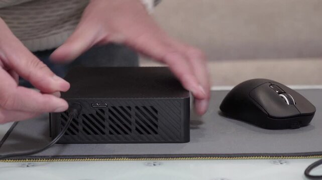 Connecting a black external hard drive, Man connecting USB cable to external hard drive