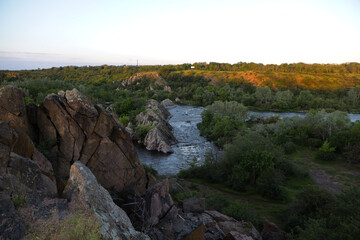 Fototapeta premium Scenic summer landscape of a fast mountain river rushing over rocks with green grassy cliffs