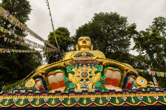 View of the golden Buddha statue adorned with intricate colorful details and surrounded by traditional prayer flags in Pokhara, Gandaki Province, Nepal.