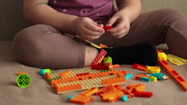 A little girl with chickenpox is playing at home with a construction kit. The child is in home isolation. Hands in close-up. Chicken pox.