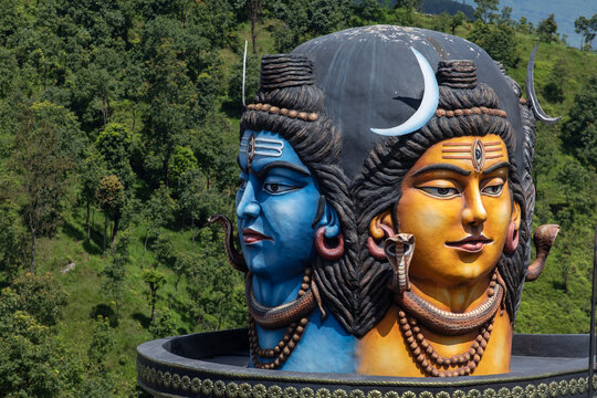 View of the large, colorful Shiva statue at Pumdikot with detailed facial features and ornate jewelry, set against a backdrop of lush green hills in Pokhara, Gandaki Province, Nepal.