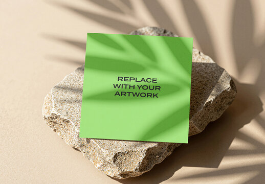Square card mockup displayed on a textured stone slab with leaf shadow, natural light, minimalist stationery branding presentation, print template, flat lay product display