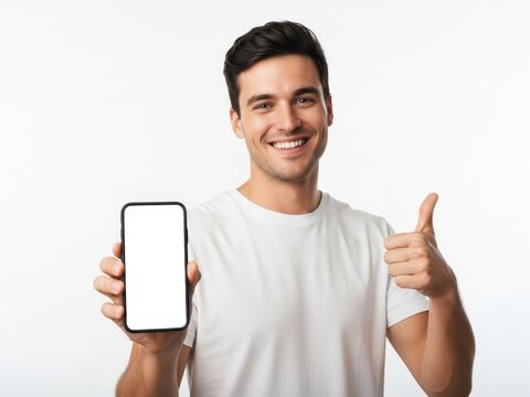 Happy young man showing a smartphone screen and giving a thumbs up gesture isolated on white background