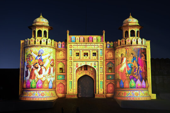 View of the Aalamgiri Gate at Lahore Fort illuminated with vibrant projection mapping art depicting traditional cultural scenes at night in Lahore, Punjab, Pakistan.