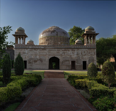 View of the historic 17th-century Tomb of Dai Anga, also known as Gulabi Bagh, featuring intricate Mughal architecture, a central dome, and a garden path in Lahore, Punjab, Pakistan.