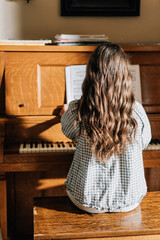 Woman playing sheet music on a piano in the sunlight © Jenisse
