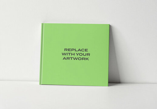 Hardcover book mockup standing upright on a white surface against plain wall, realistic cover presentation with natural lighting, template for graphic design and print media