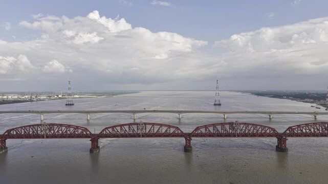 Drone footage moving from right to left reveals Hardinge Bridge and Lalon Shah Bridge spanning the wide Padma River, with large volumes of muddy water flowing beneath the bridges in Bangladesh.