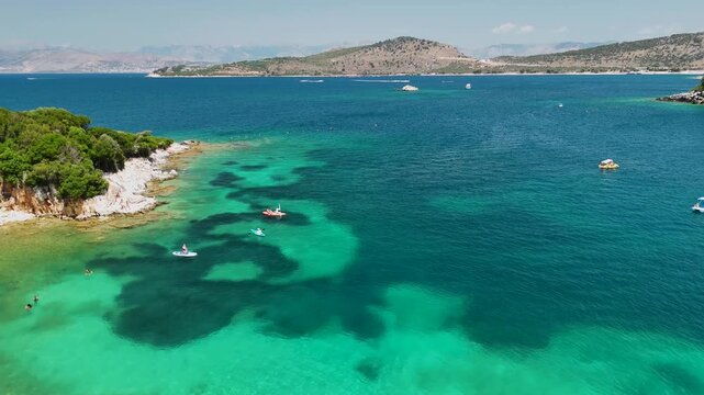 Woman on sup board in Ksamil near Twin Islands, Ionian Sea, Saranda, Albania. Stand up paddle board woman paddle boarding. Aerial panoramic drone view from above, top view from drone. Mediterranean se
